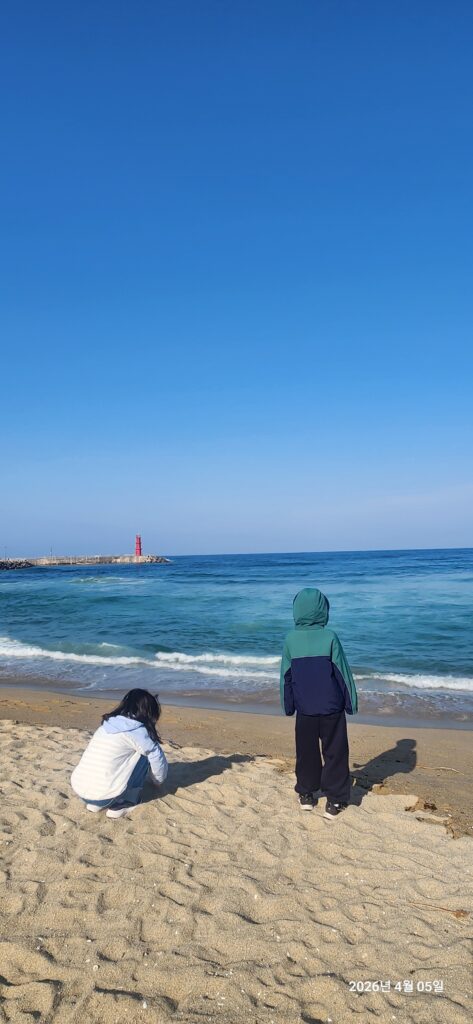 Two children looking at the ocean on Sokcho Beach, a visual example for a trip from seoul to gangwon-do.