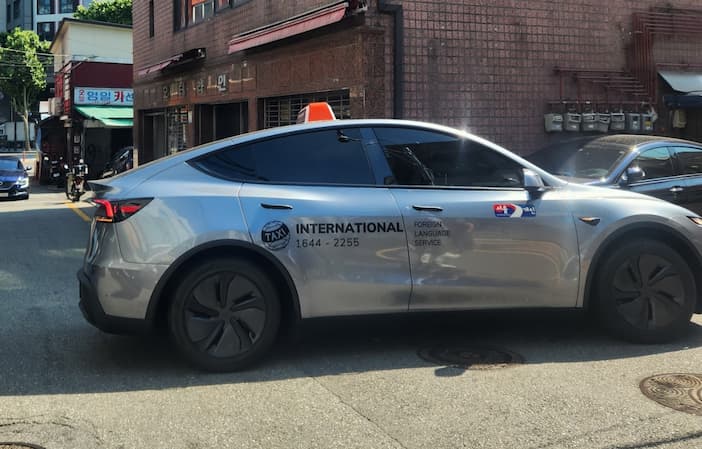 International Taxi Seoul — foreign language service sign on a Tesla taxi in Jongno